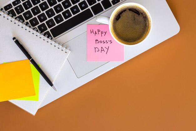 Le concept de la journée du patron est l'ordinateur portable et une tasse de café sur la table.