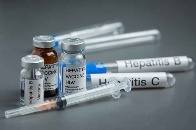 Concept de la journée mondiale de l'hépatite avec des outils médicaux et des pilules placés sur une surface grise