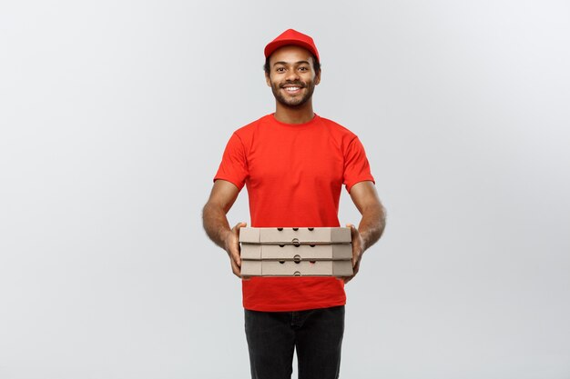 Concept de livraison - Portrait de Handsome African American Pizza Delivery Man. Isolé sur fond de studio gris. Espace de copie.