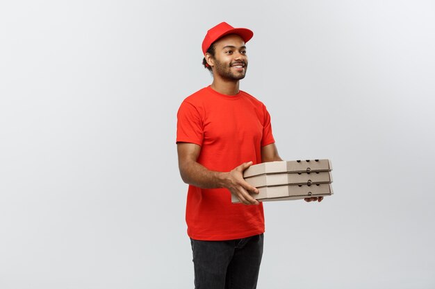 Concept de livraison - Portrait de Handsome African American Pizza Delivery Man. Isolé sur fond de studio gris. Espace de copie.