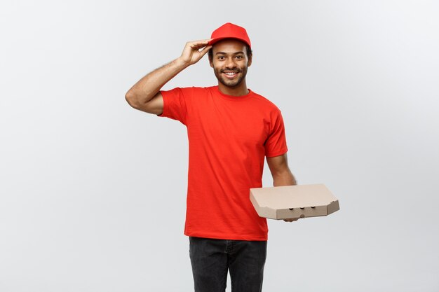 Concept de livraison - Portrait de Handsome African American Pizza Delivery Man. Isolé sur fond de studio gris. Espace de copie.