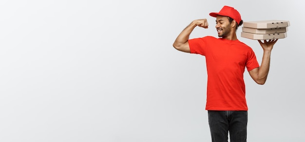 Photo gratuite concept de livraison portrait d'un livreur afro-américain fort montrant son muscle avec des paquets de boîte à pizza isolé sur fond gris studio espace de copie