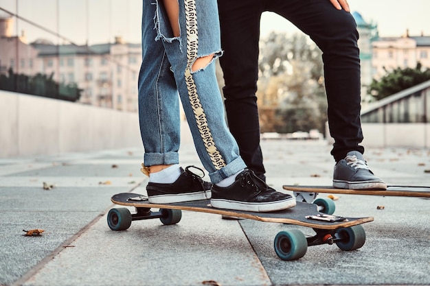 Concept de loisirs et de sport - photo en gros plan d'un couple d'adolescents habillé à la mode avec des planches à roulettes dans la rue.