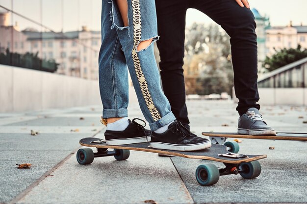 Concept de loisirs et de sport - photo en gros plan d'un couple d'adolescents habillé à la mode avec des planches à roulettes dans la rue.