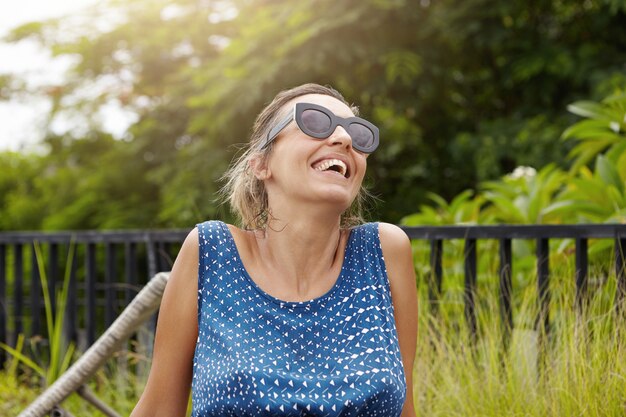 Concept de maternité heureux. Tête de belle femme enceinte dans les tons passant du bon temps à l'extérieur, respirer l'air frais et rire, rejetant la tête sur les arbres verts