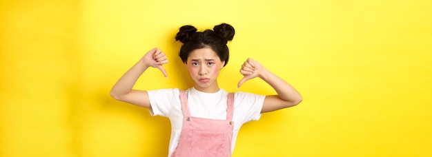 Photo gratuite concept de mode de vie d'été femme asiatique triste et sombre avec du maquillage pointant les doigts vers le bas et fronçant les sourcils u