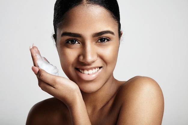 Concept de nettoyage de la peau femme souriante avec une mousse sur la main