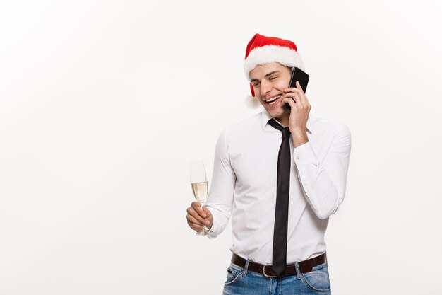 Concept de Noël Bel homme d'affaires parlant au téléphone et tenant un verre de champagne célébrant Noël et le Nouvel An