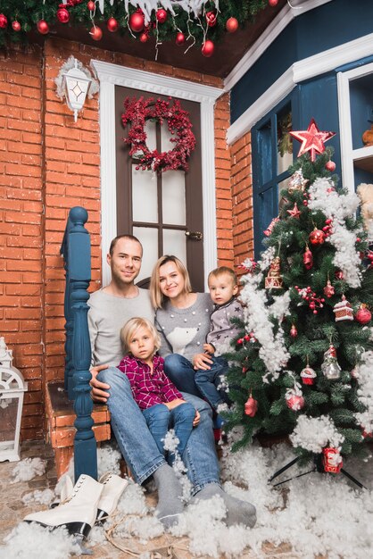 Concept de Noël avec la famille assis en face de la maison