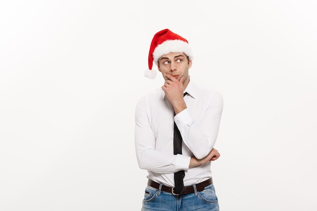 Concept de Noël Handsome Business man wear santa hat posant avec une expression faciale réfléchie sur fond isolé blanc