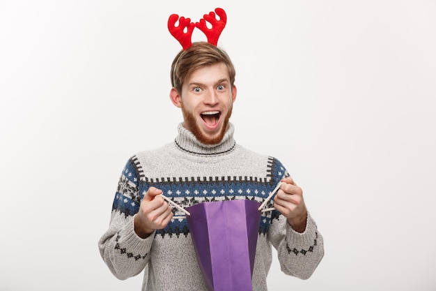Concept de Noël jeune bel homme barbe heureux avec sac à provisions dans la main isolé sur blanc