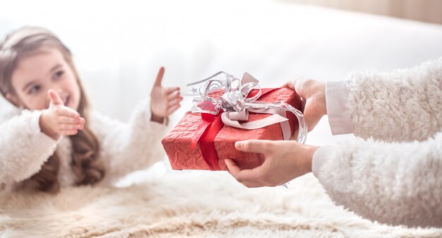 Concept de Noël, maman donne un cadeau à une petite fille mignonne, une place pour le texte sur un fond clair