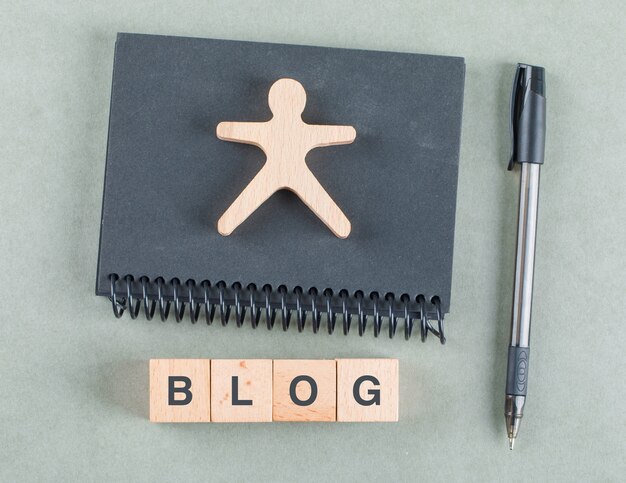 Concept de notes de blog avec des blocs en bois, stylo et vue de dessus de cahier noir.