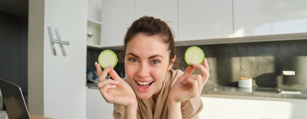 Concept de nourriture et de style de vie belle femme cuisinant dans la cuisine tenant des courgettes crues et souriant