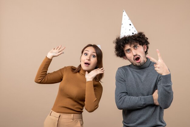 Concept de nouvel an avec un beau jeune couple heureux excité porter chapeau de nouvel an fille et gars sur gris