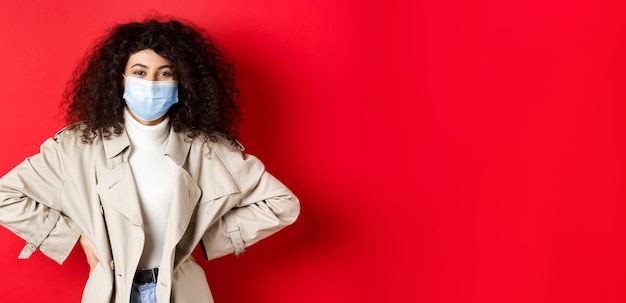 Photo gratuite concept de pandémie et de quarantaine covid femme moderne élégante aux cheveux bouclés portant un trench-coat et m