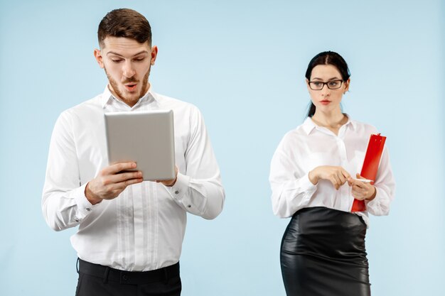 Concept de partenariat en entreprise. Jeune homme émotionnel et femme sur fond bleu au studio. Concept d'émotions humaines et de partenariat