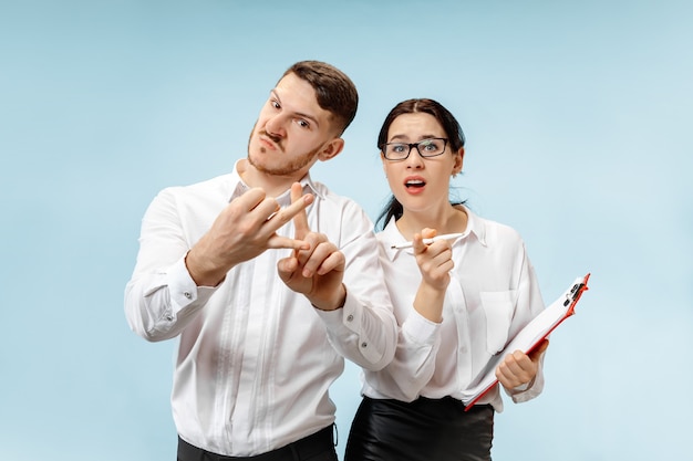 Concept de partenariat en entreprise. Jeune homme émotionnel et femme sur fond bleu au studio. Concept d'émotions humaines et de partenariat