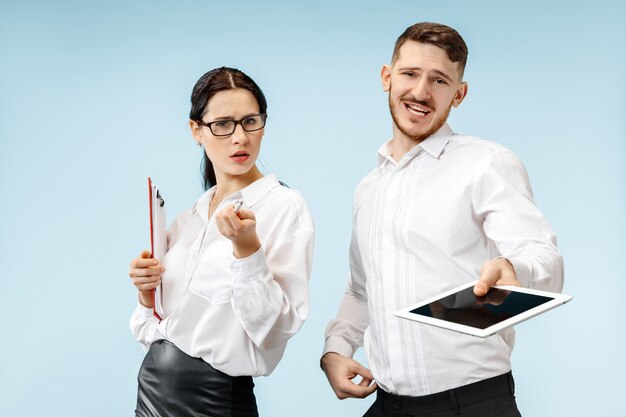 Concept de partenariat en entreprise. Jeune homme et femme émotionnelle contre le mur bleu. Concept d'émotions humaines et de partenariat