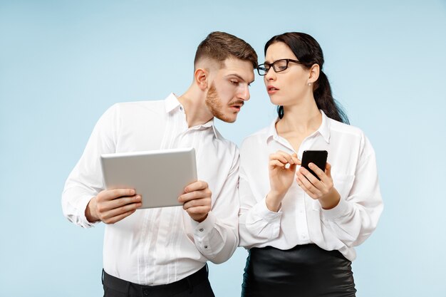 Concept de partenariat en entreprise. Jeune homme et femme émotionnelle contre le mur bleu. Concept d'émotions humaines et de partenariat