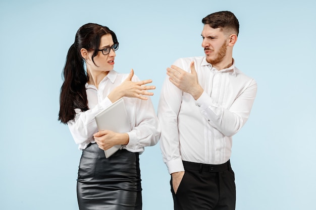 Concept de partenariat en entreprise. Jeune homme et femme émotionnelle contre le mur bleu à. Concept d'émotions humaines et de partenariat