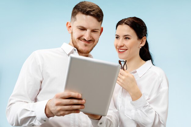 Concept de partenariat en entreprise. Jeune homme souriant heureux et femme debout contre le mur bleu