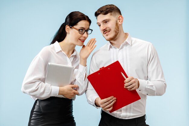 Concept de partenariat en entreprise. Jeune homme souriant heureux et femme debout sur fond bleu au studio