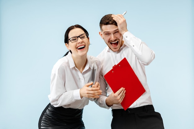 Concept de partenariat en entreprise. Jeune homme souriant heureux et femme debout sur fond bleu au studio