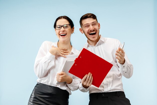 Concept de partenariat en entreprise. Jeune homme souriant heureux et femme debout sur fond bleu