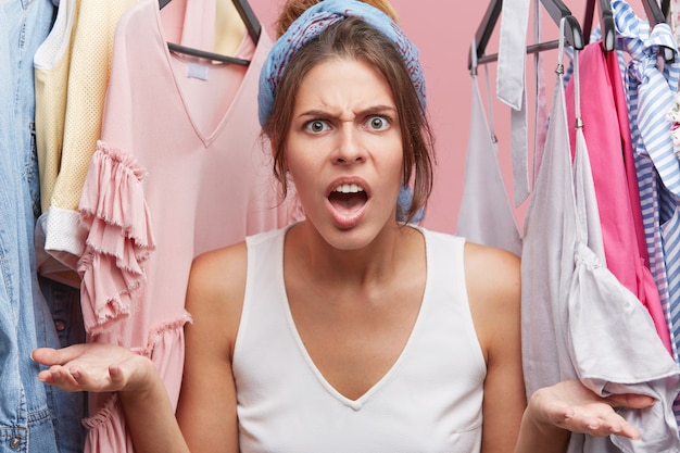 Concept de personnes, d'émotions négatives et d'expressions faciales. Femme en colère sreaming au vendeur dans un magasin de vêtements qui la sert très mal. Femme criant debout dans la cabine d'essayage du magasin de vêtements