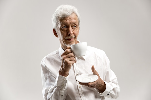 Concept de personnes - homme senior heureux avec une tasse de thé au studio. Concept d'émotions humaines