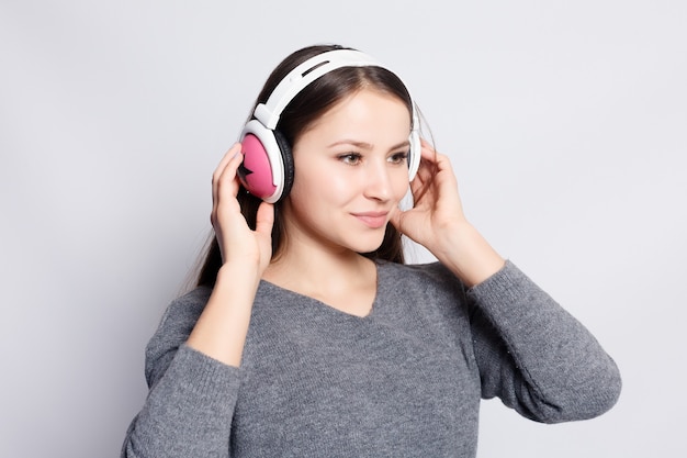 Concept de personnes, de loisirs et de technologie - femme heureuse ou adolescente dans des écouteurs écoutant de la musique à partir d'un smartphone et dansant
