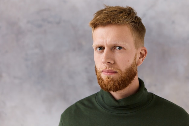 Photo gratuite concept de personnes, de style et de mode. photo de séduisant jeune homme mal rasé à la mode ayant une expression faciale grave, ne peut pas cacher les soupçons,