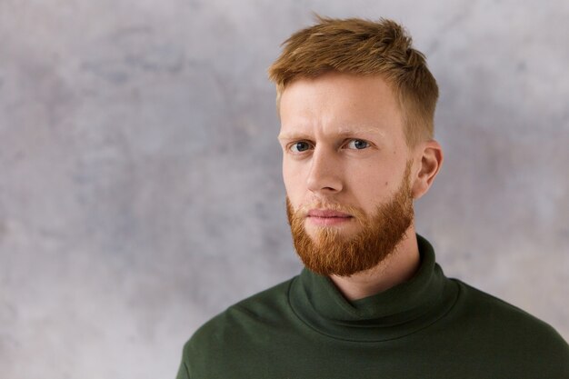 Concept de personnes, de style et de mode. Photo de séduisant jeune homme mal rasé à la mode ayant une expression faciale grave, ne peut pas cacher les soupçons,