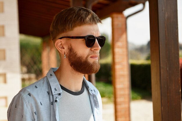 Concept de personnes et de style de vie. Séduisante jeune homme de race blanche avec une longue barbe rouge portant des lunettes de soleil noires