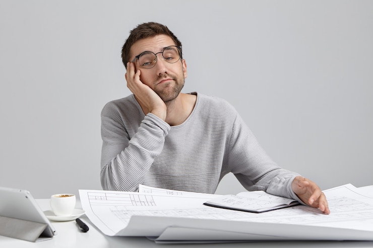 Photo gratuit concept de personnes, de travail, de fatigue et de surmenage. ingénieur masculin endormi ennuyé travaillant sur des plans