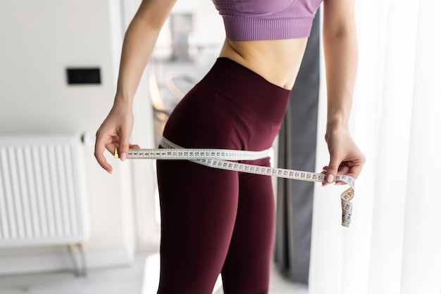 Concept de régime. Femme avec ruban à mesurer dans la chambre à la maison