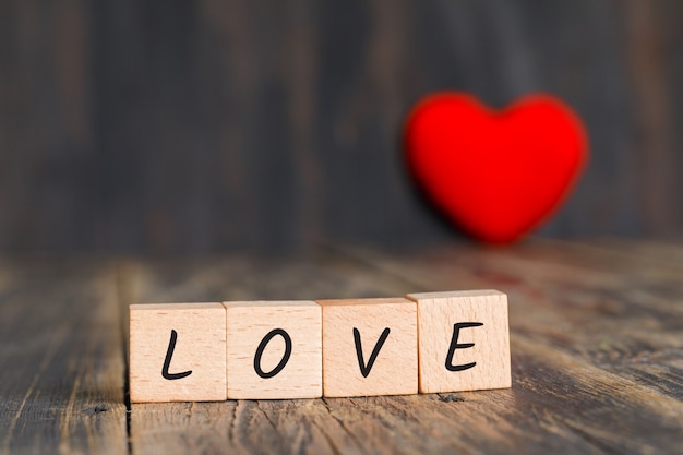 Concept de relation avec coeur rouge, cubes en bois sur vue de côté de table en bois.