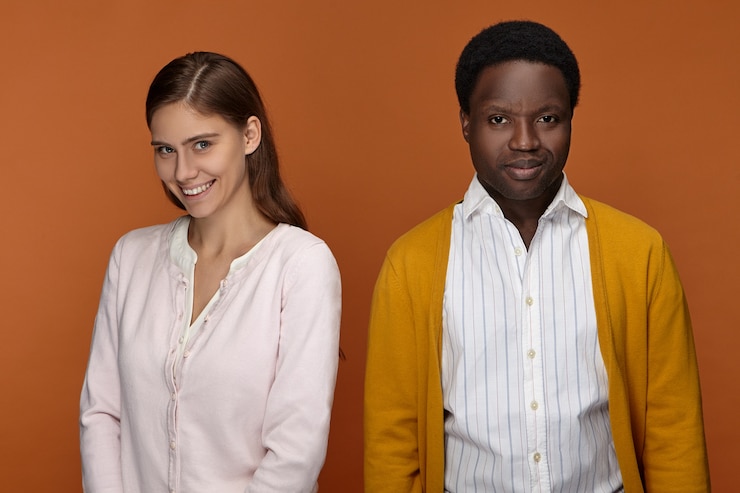 Photo gratuit concept de relations interraciales, d'amour, d'amitié et de partenariat. portrait d'heureuse jeune femme européenne confiante avec un large sourire posant avec son collègue masculin africain