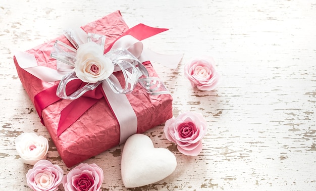 Photo gratuite concept de la saint-valentin et de la fête des mères, coffret rouge avec noeud et roses sur fond de bois clair