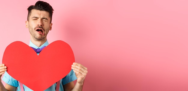 Concept de la Saint-Valentin homme triste et solitaire se sentant le cœur brisé d'être rejeté montrant un grand coeur rouge c