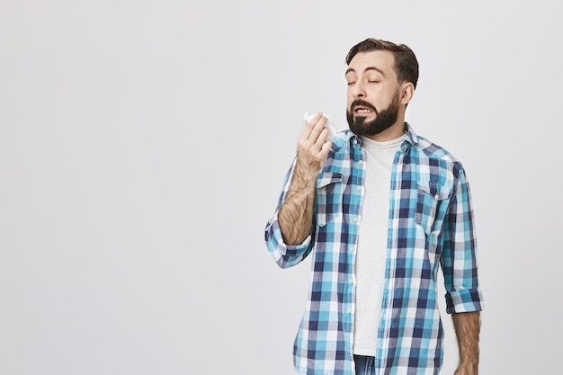 Photo gratuite concept de santé. homme malade ayant une allergie, éternuant dans une serviette