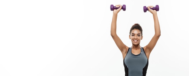 Concept de santé et de remise en forme belle dame africaine américaine en vêtements de fitness séance d'entraînement avec haltère