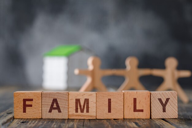 Concept de sécurité familiale avec des figures en bois de personnes, cubes, vue de côté de la maison modèle.