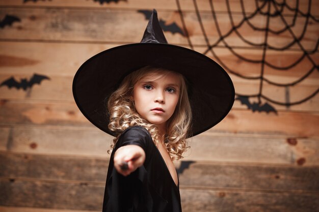 Concept de sorcière d'Halloween, petit enfant de sorcière aime jouer avec une baguette magique sur une chauve-souris et une toile d'araignée...