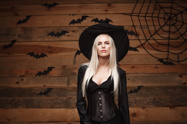 Concept de sorcière Halloween sorcière sexy halloween heureux tenant posant sur fond de studio en bois ancien