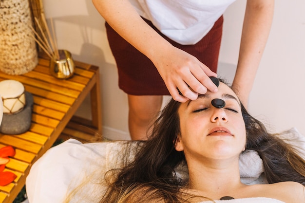 Concept de spa avec une femme avec de longs cheveux noirs et de la pierre dans le visage