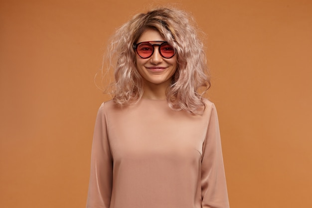 Concept De Style, Mode Et Jeunesse. Adorable Jeune Femme Européenne à La Mode à La Mode Avec Des Cheveux Rosés En Désordre Posant En Portant Un Chemisier élégant Et Des Lunettes De Soleil