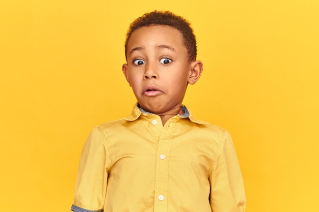 Concept de surprise, d'étonnement et de choc. Image isolée de petit garçon afro-américain étonné choqué exprimant une vraie réaction surprise, grimaçant tout en regardant quelque chose de dégoûtant