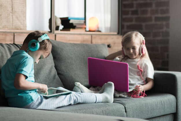 Concept de technologie avec deux enfants sur le canapé